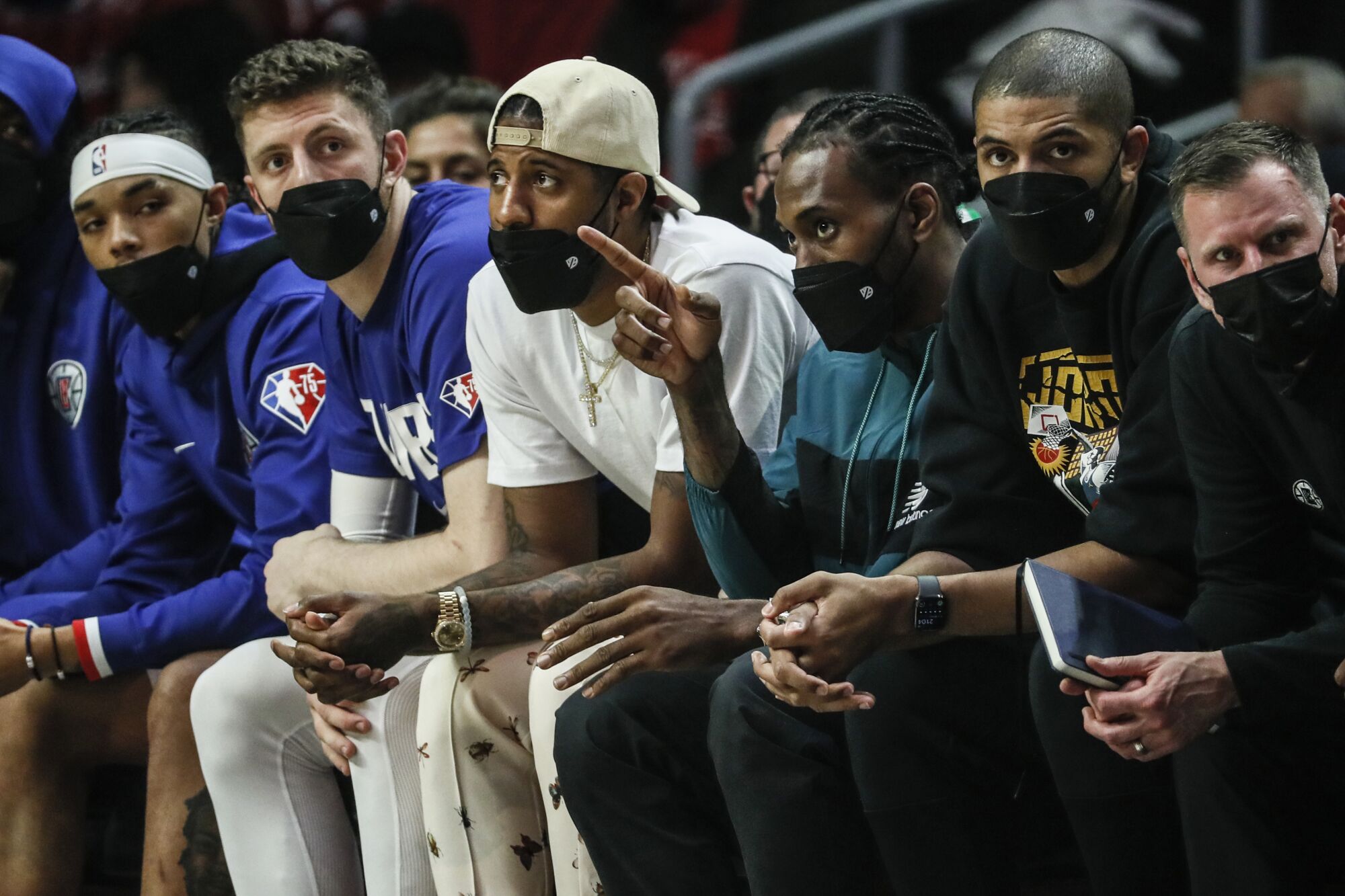 Clippers player Kawhi Leonard points to the field while seated next to teammate Paul George.