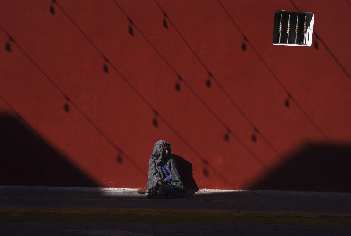 An Indigenous woman sits on a sidewalk in Izucar de Matamoros in the Mexican state of Puebla, Wednesday, June 29, 2022. (AP Photo/Marco Ugarte)