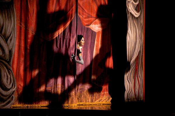 A performer peeks through the curtain as "Iris," a show about Hollywood by Cirque du Soleil, began a long run at the Kodak Theatre.