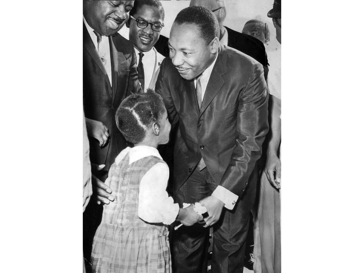 Oct. 27, 1964: King pauses to chat with a young girl during a tour of the Nickerson Gardens housing project.