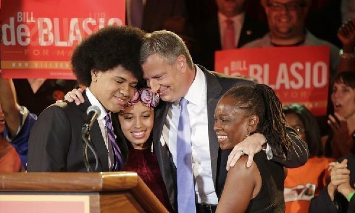 In this Sept. 10, 2013 file photo, New York Democratic mayoral candidate Bill de Blasio embraces his son Dante, left, daughter Chiara, second from left, and wife Chirlane McCray, right, after polls closed in the city's primary election in New York.