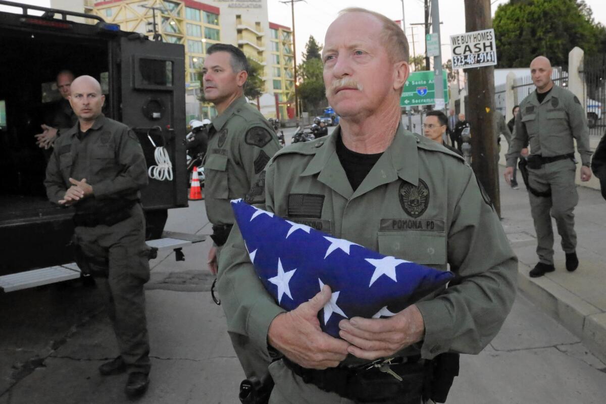 Pomona police Officer David Sevesind holds a folded American flag after he and fellow law enforcement officers escorted the body of SWAT team member Shaun Richard Diamond to the county coroner's office on Wednesday.