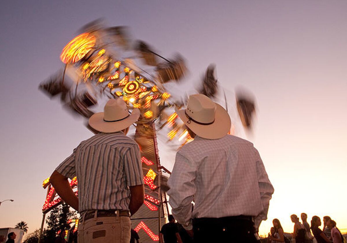 Fernando Molina, left, and Carlos Mora, both of Tulare, watch the Zipper ride at the Tulare County Fair. The Zipper formerly operated at Michael Jackson's Neverland Ranch and now is owned by Helm and Sons, which operates carnival rides.