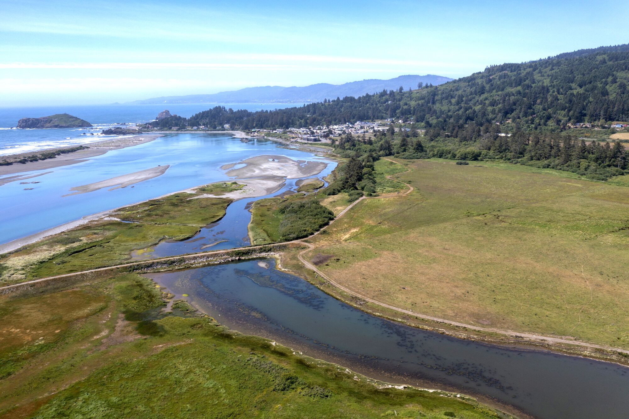 Aerial view of the Smith River estuary running through land into the ocean.