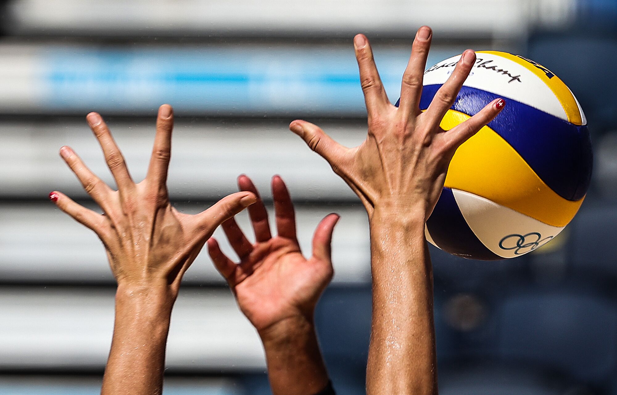A closeup of hands and a volleyball in the air.