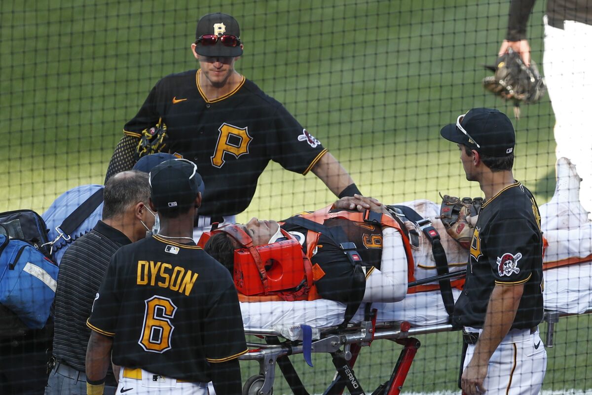 Pittsburgh Pirates Kevin Newman, top, Adam Frazier, right, and Jarrod Dyson (6) check on Phillip Evans (64) as he is taken from the filed on a stretcher after he collided with Gregory Polanco along the right field fence while chasing a fly ball by Detroit Tigers' Miguel Cabrera in the sixth inning of a baseball game Saturday, Aug. 8, 2020, in Pittsburgh. Polanco stayed in the game. (AP Photo/Keith Srakocic)