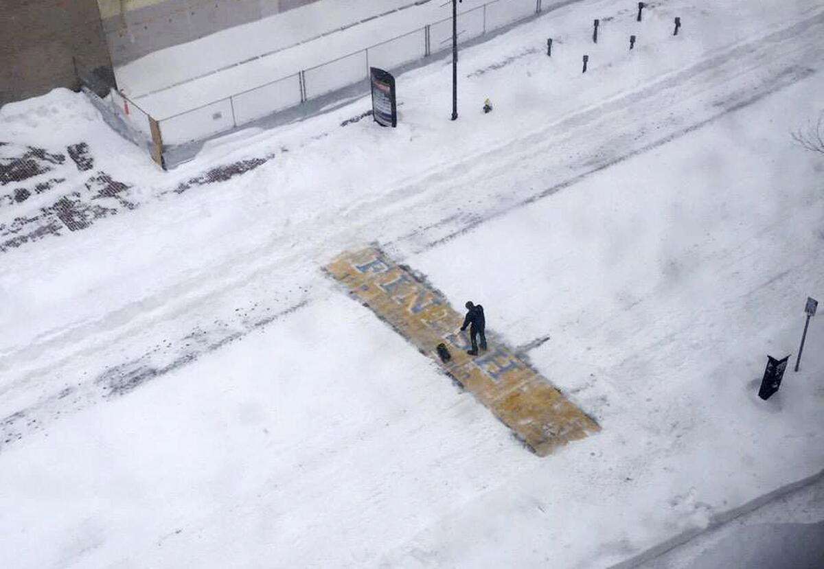A man shovels snow off the finish line of the Boston Marathon. A social media campaign helped identify him as Chris Laudani, a local bartender.