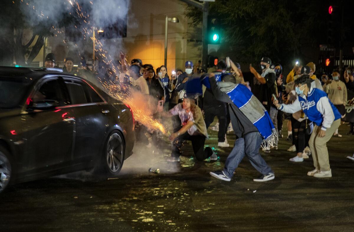 Dodgers fans light off fireworks behind a car doing donuts at Sunset and Figueroa after the World Series win