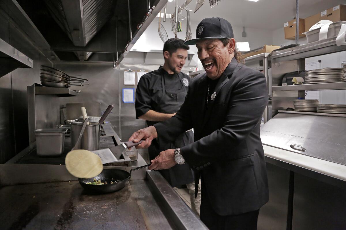 El actor Danny Trejo, a la derecha, y el chef John-Carlos Kuramoto cocinan su taco vegano de coliflor en Trejo's Cantina.