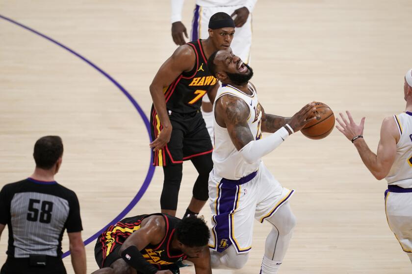 Los Angeles Lakers forward LeBron James, center, grimaces as he trips and injures himself over Atlanta Hawks forward Tony Snell, bottom, during the first half of an NBA basketball game Saturday, March 20, 2021, in Los Angeles. (AP Photo/Marcio Jose Sanchez)