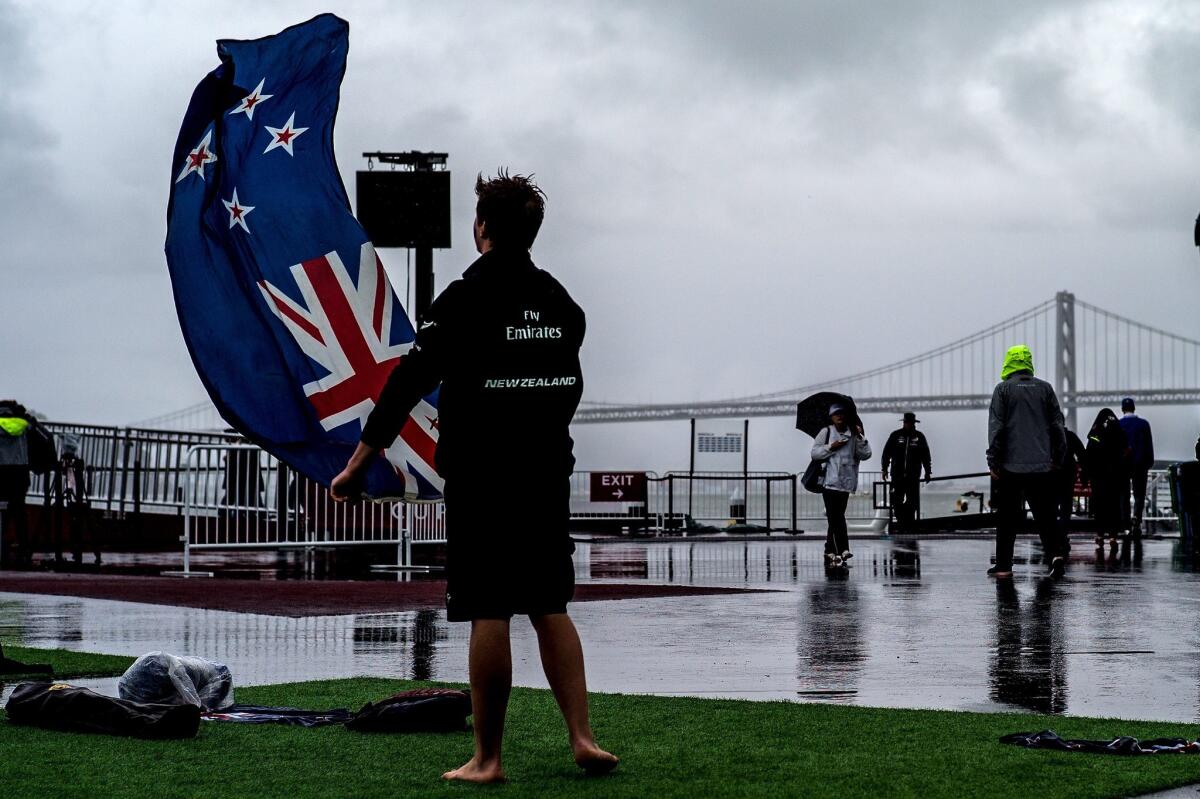 A New Zealand fan waves the country's flag while waiting for the start of Race 14 of the America's Cup, which was postponed Saturday due to wind conditions.