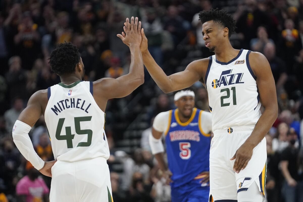Utah Jazz's Donovan Mitchell (45) and Hassan Whiteside (21) high-five during the first half of the team's NBA basketball game against the Golden State Warriors on Wednesday, Feb. 9, 2022, in Salt Lake City. (AP Photo/Rick Bowmer)