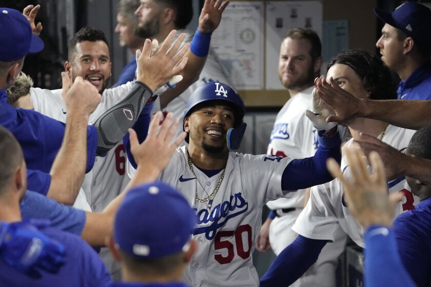 Mookie Betts, de los Dodgers de Los Ángeles, recibe la felicitación en la cueva tras batear un jonrón en el juego del martes 1 de agosto de 2023, ante los Atléticos de Oakland (AP Foto/Mark J. Terrill)