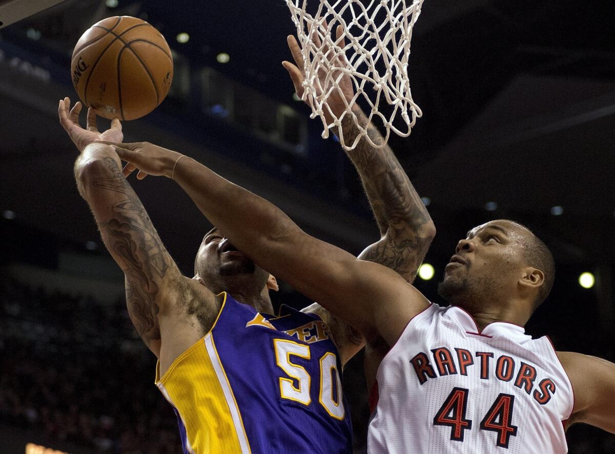 Raptors forward Chuck Hayes blocks the shot of Lakers center Robert Sacre in the first half of a 2014 game.