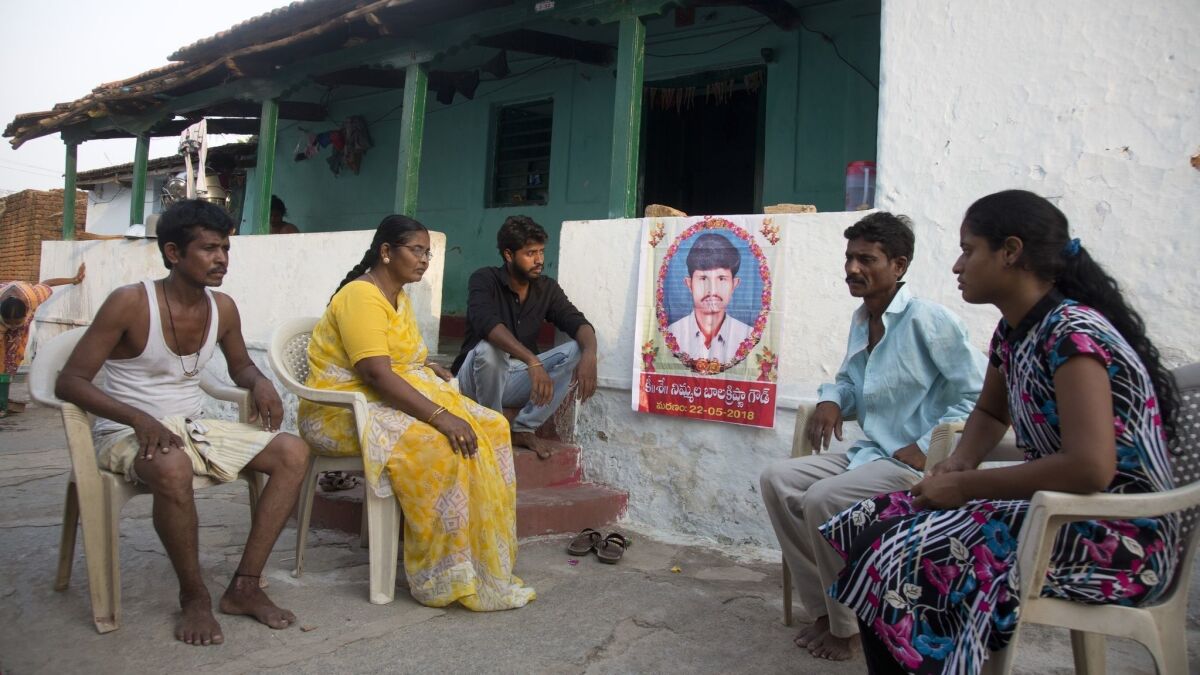 Family members gather by a portrait of Bala Krishna, a 33-year-old motorized rickshaw driver who was killed by a mob responding to social media messages about gangs of kidnappers looking for children.
