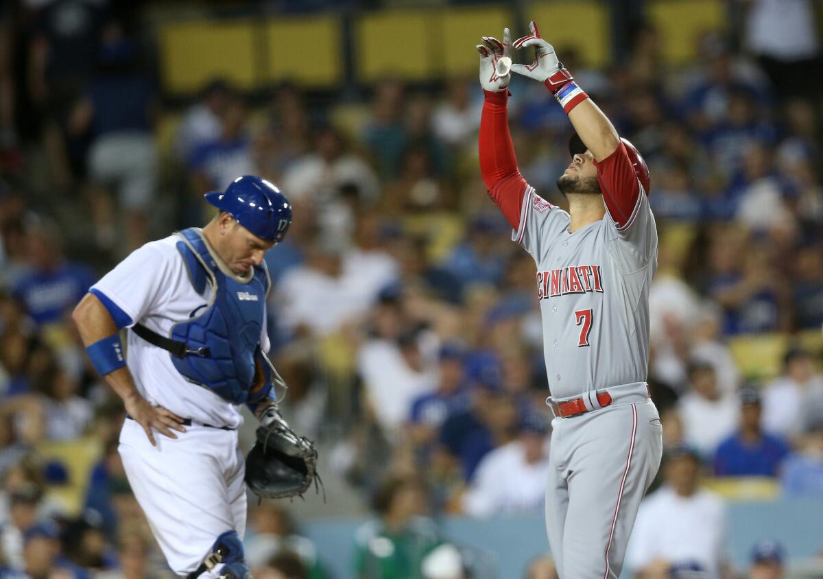 Reds shortstop Eugenio Suarez points to the sky after crossing the plate on his three-run home run while Dodgers catcher A.J. Ellis looks at the ground at Dodger Stadium on Aug 13.