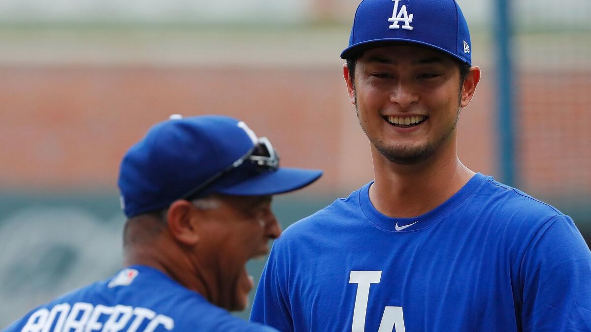 New Dodgers pitcher Yu Darvish, right, jokes around with Manager Dave Roberts prior to a game against the Atlanta Braves on Aug. 2.