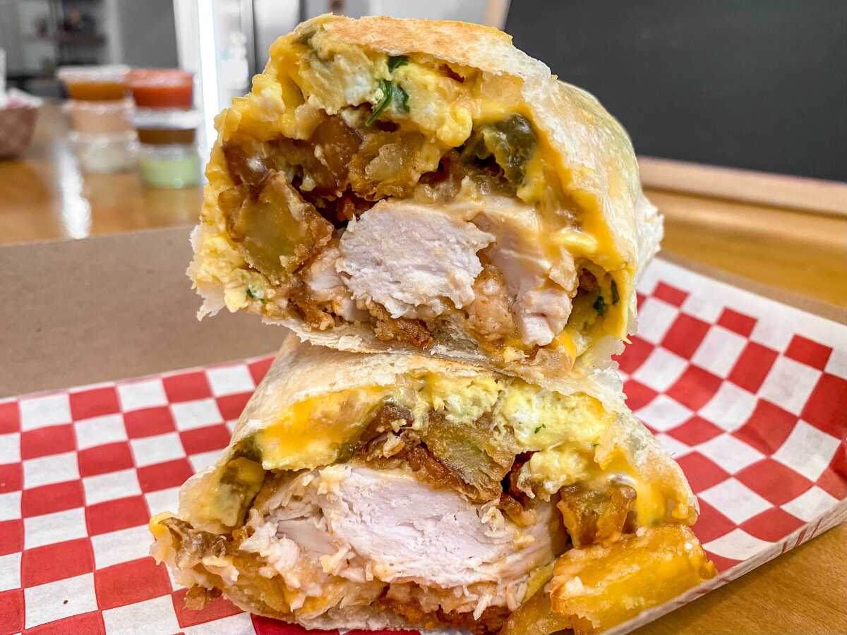 A chicken, bacon and egg burrito cut in half.