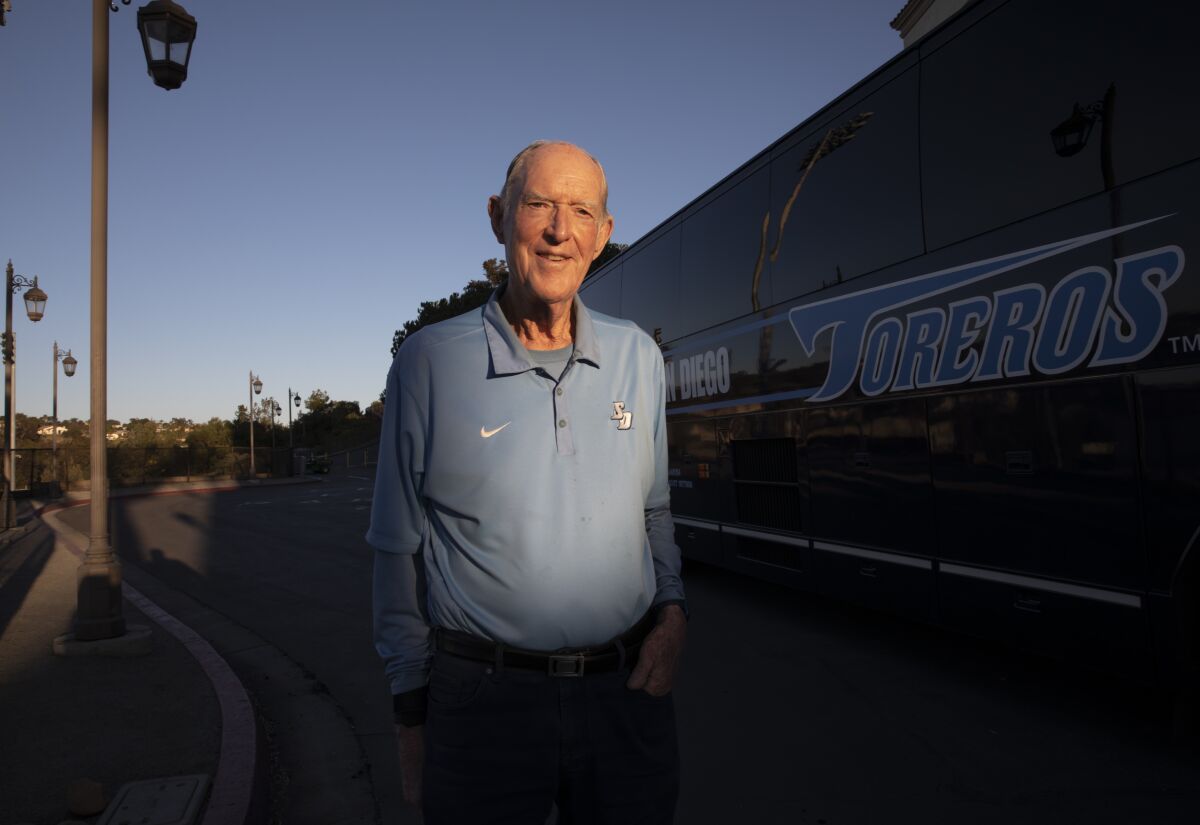 John Cunningham stands in front of the USD athletics bus.