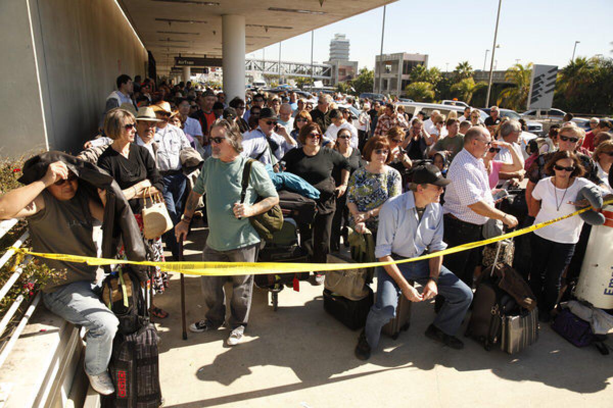 Passengers wait outside Terminal 1 at LAX after a Transportation Security Administration agent was shot and several other people were wounded when a gunman opened fire in a Los Angeles International Airport terminal Nov. 1.