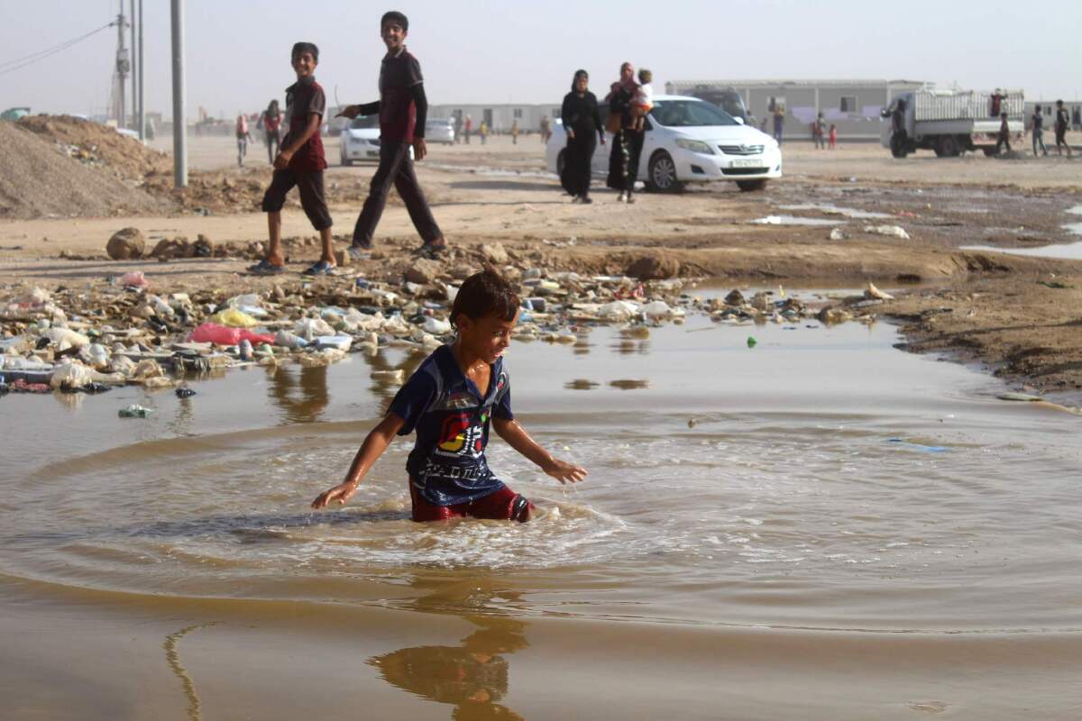 A displaced Iraqi boy plays in a puddle of water at a camp in Amiriyah al-Fallouja on June 22, 2016.