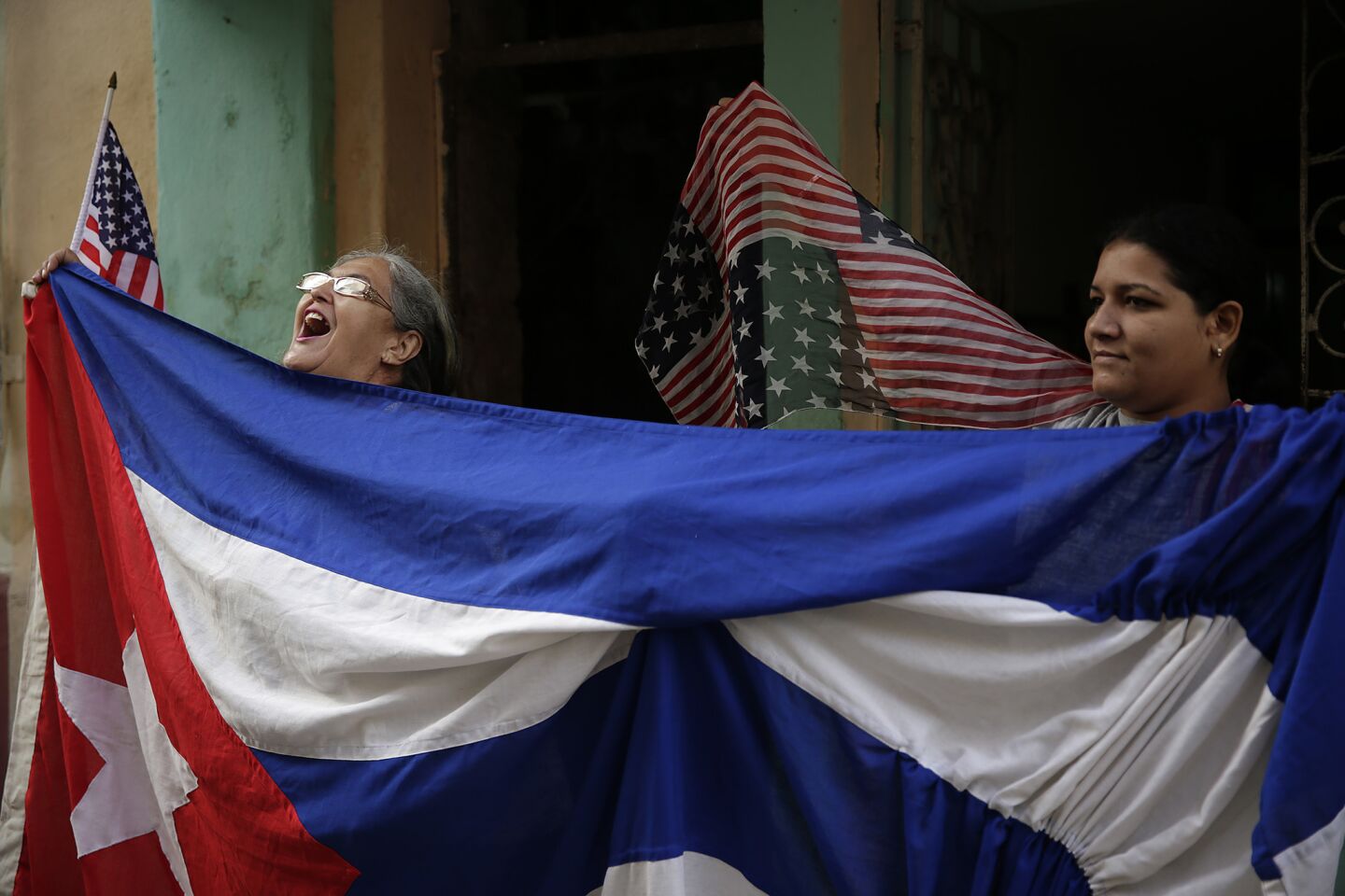 Maria Castro, left, and Laritza Mojenas cheer for President Obama from the front door of a Havana home.