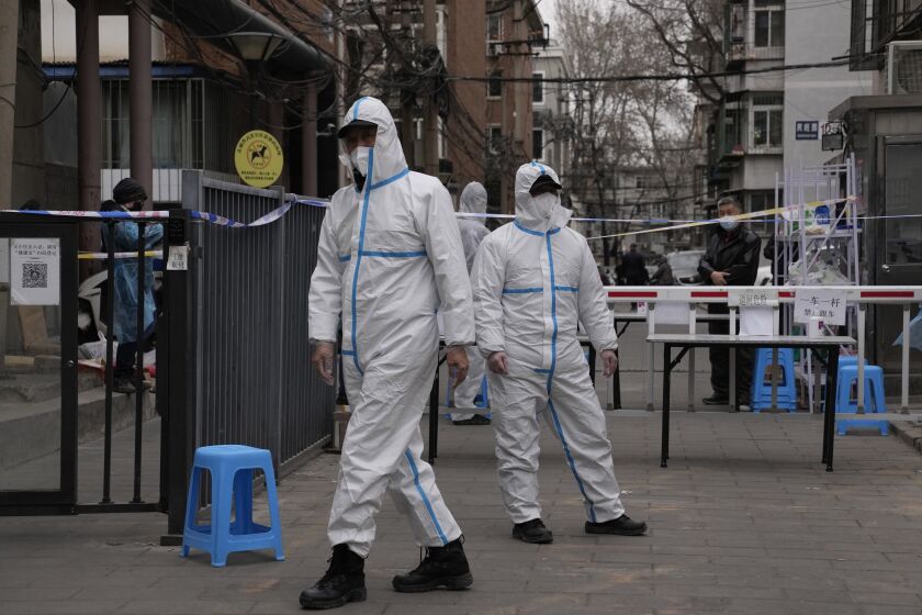 Workers in PPE overalls guard an entrance to a community under lock down on Thursday, March 17, 2022, in Beijing. A fast-spreading variant known as "stealth omicron" is testing China's zero-tolerance strategy, which had kept the virus at bay since the deadly initial outbreak in the city of Wuhan in early 2020. (AP Photo/Ng Han Guan)