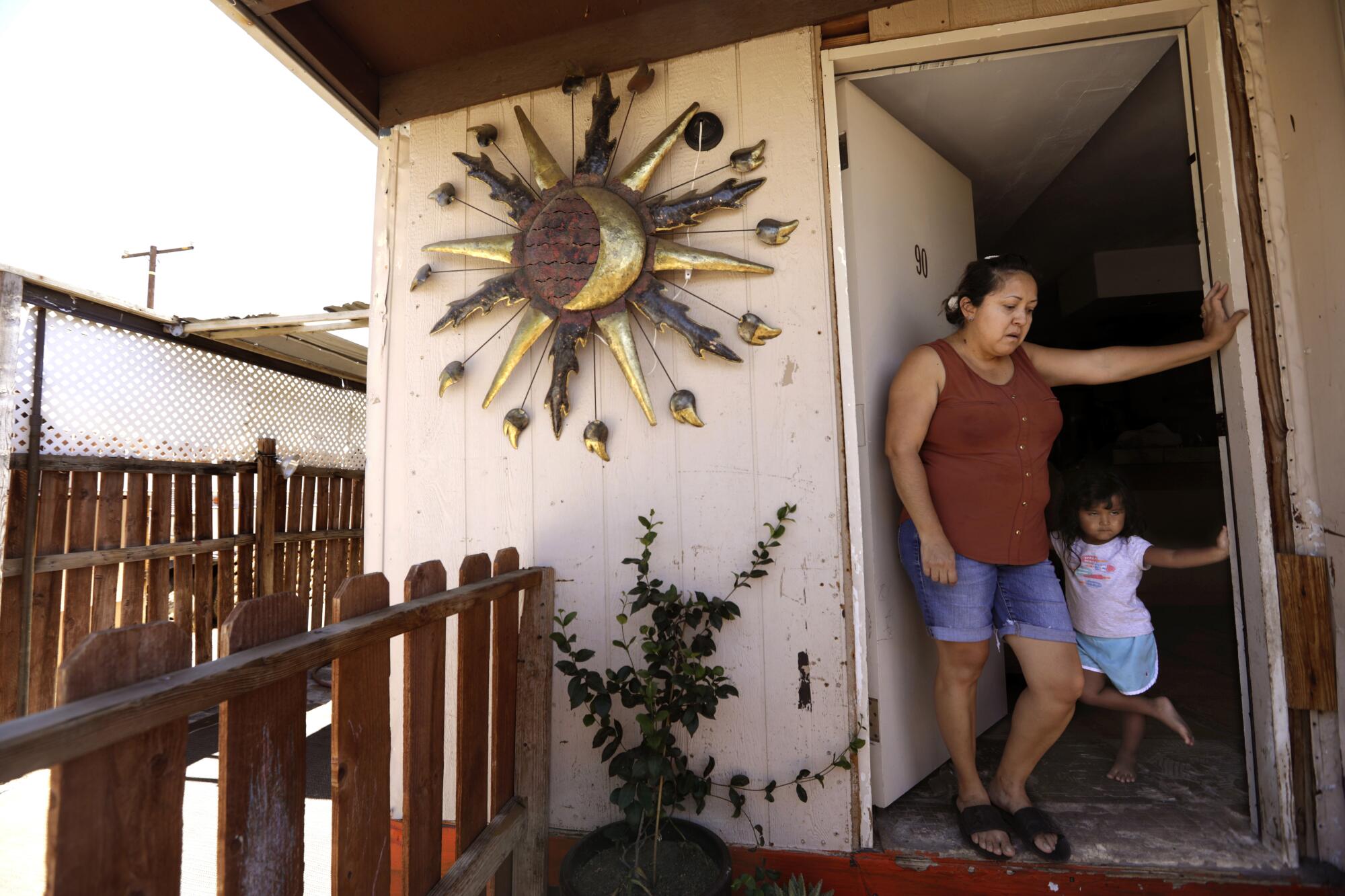 Emma Duarte and her daughter stand in the doorway of their mobile home