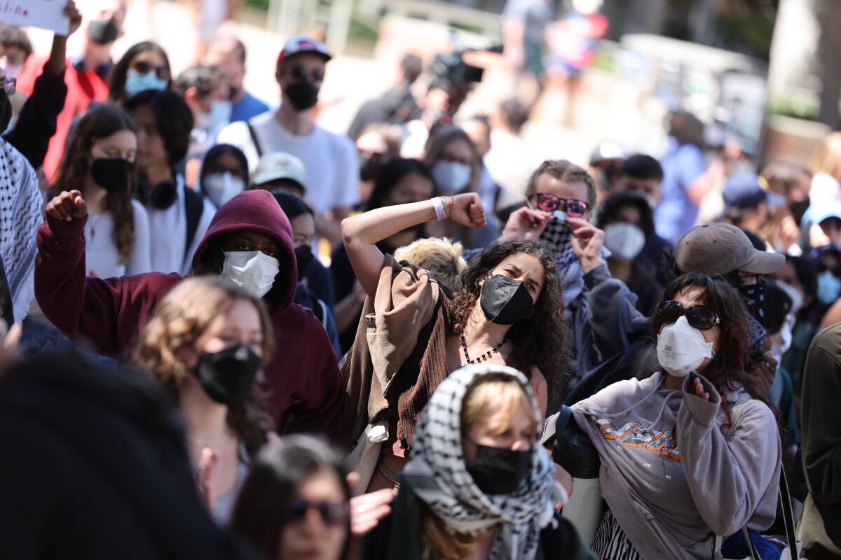 Students wearing masks and keffiyehs protest. 