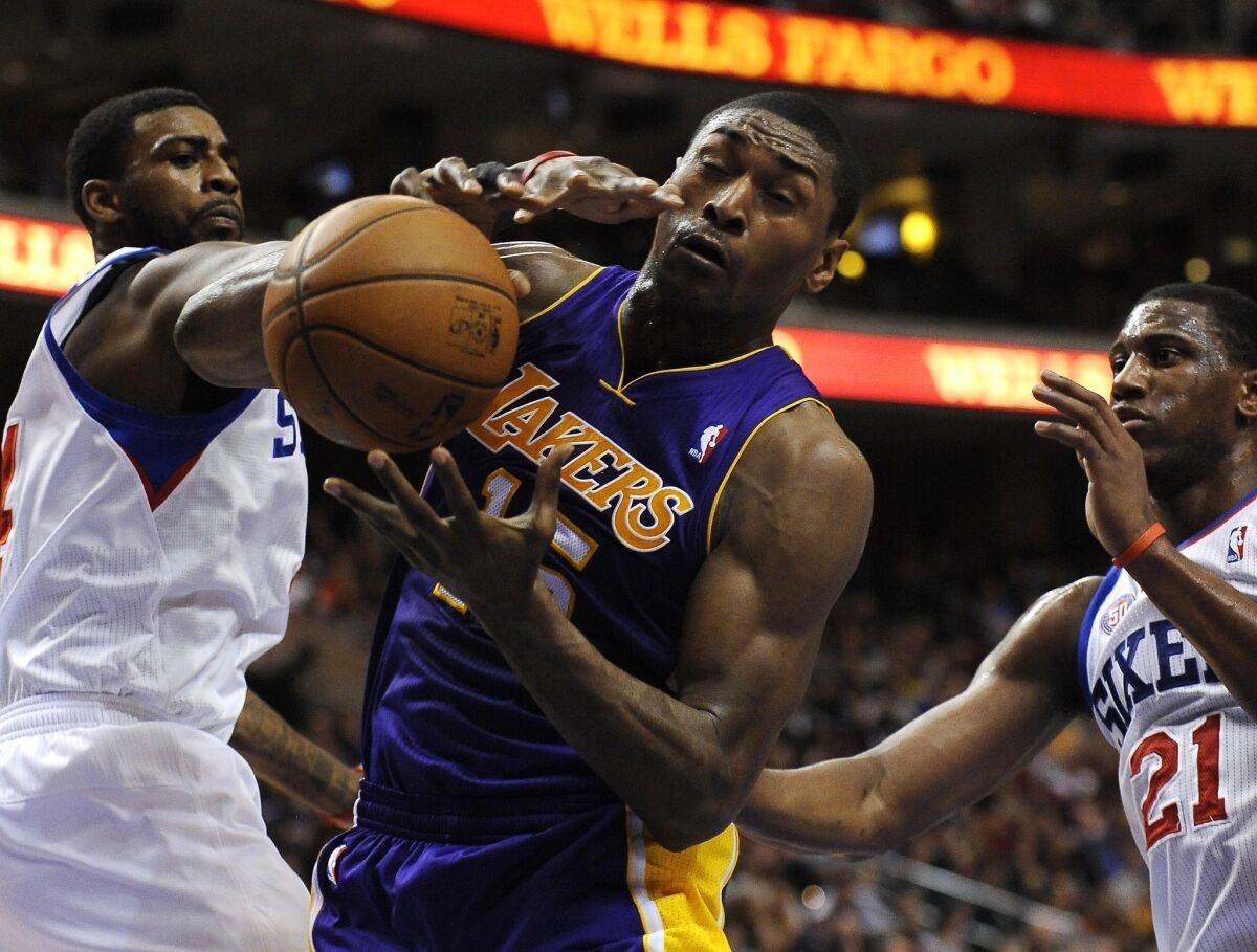 Metta World Peace pulls in a rebound against the Philadelphia 76ers' Dorrell Wright and Thaddeus Young.