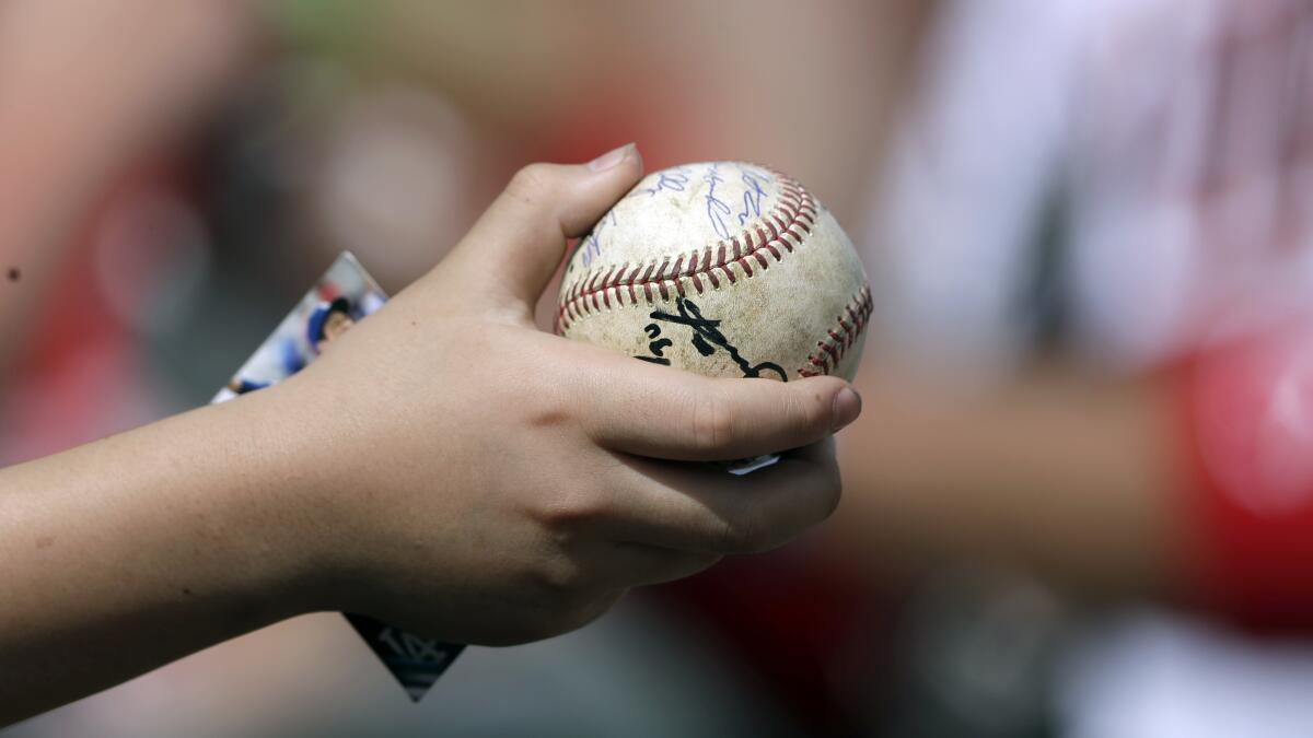 A young fan holds a baseball in hopes of getting an autograph before a spring training game between the Minnesota Twins and the Boston Red Sox on Monday, in Fort Myers, Fla.