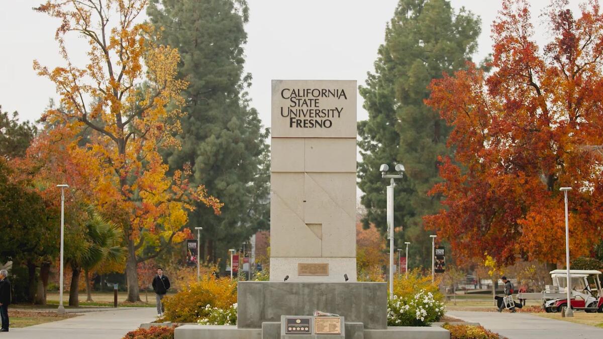 A tall sign reading "California State University Fresno," with multicolored trees in the background.