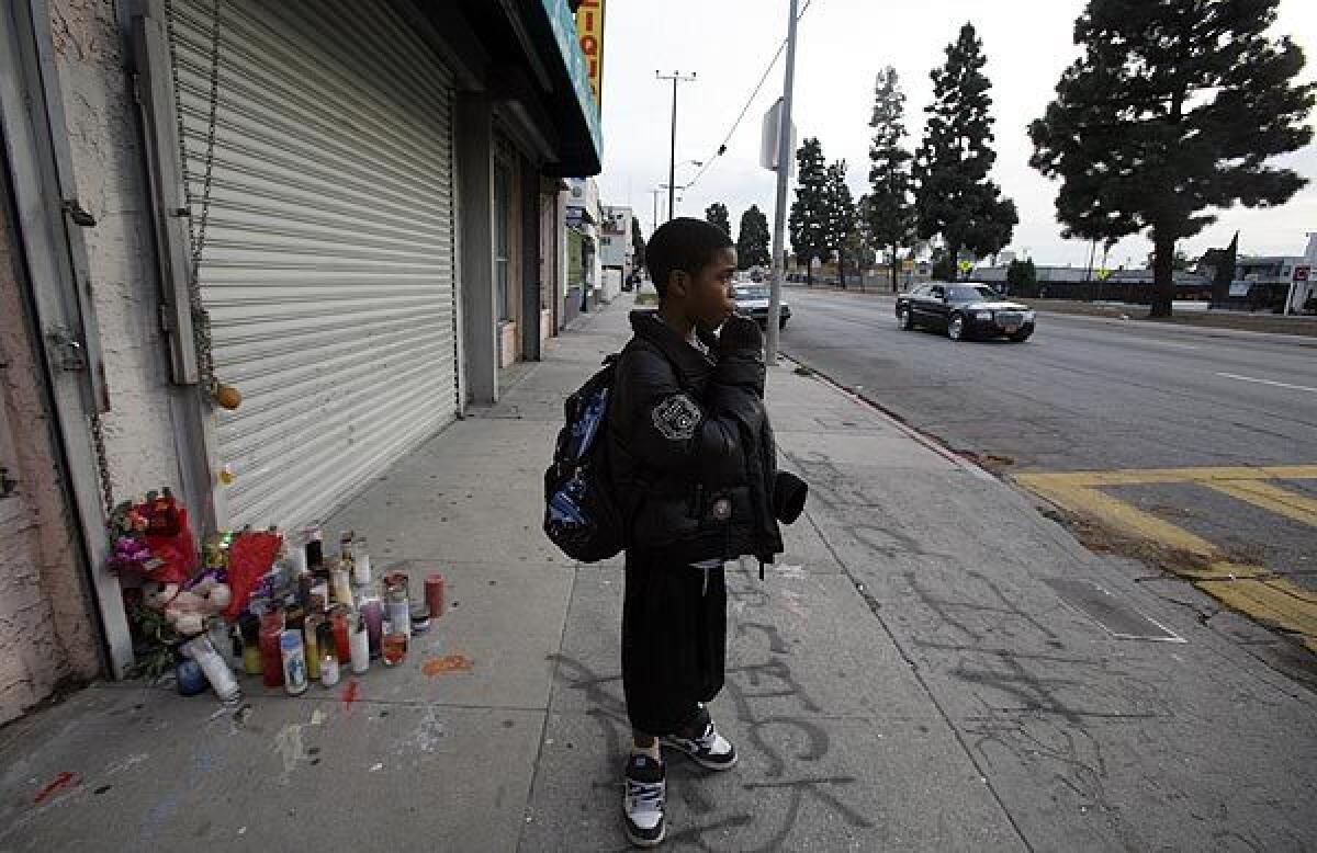 Keionta Hayes, 12, stands before a memorial of candles in the 10500 block of South Vermont Avenue, where his friend was shot earlier this month. The area is one of the deadliest in Los Angeles County.