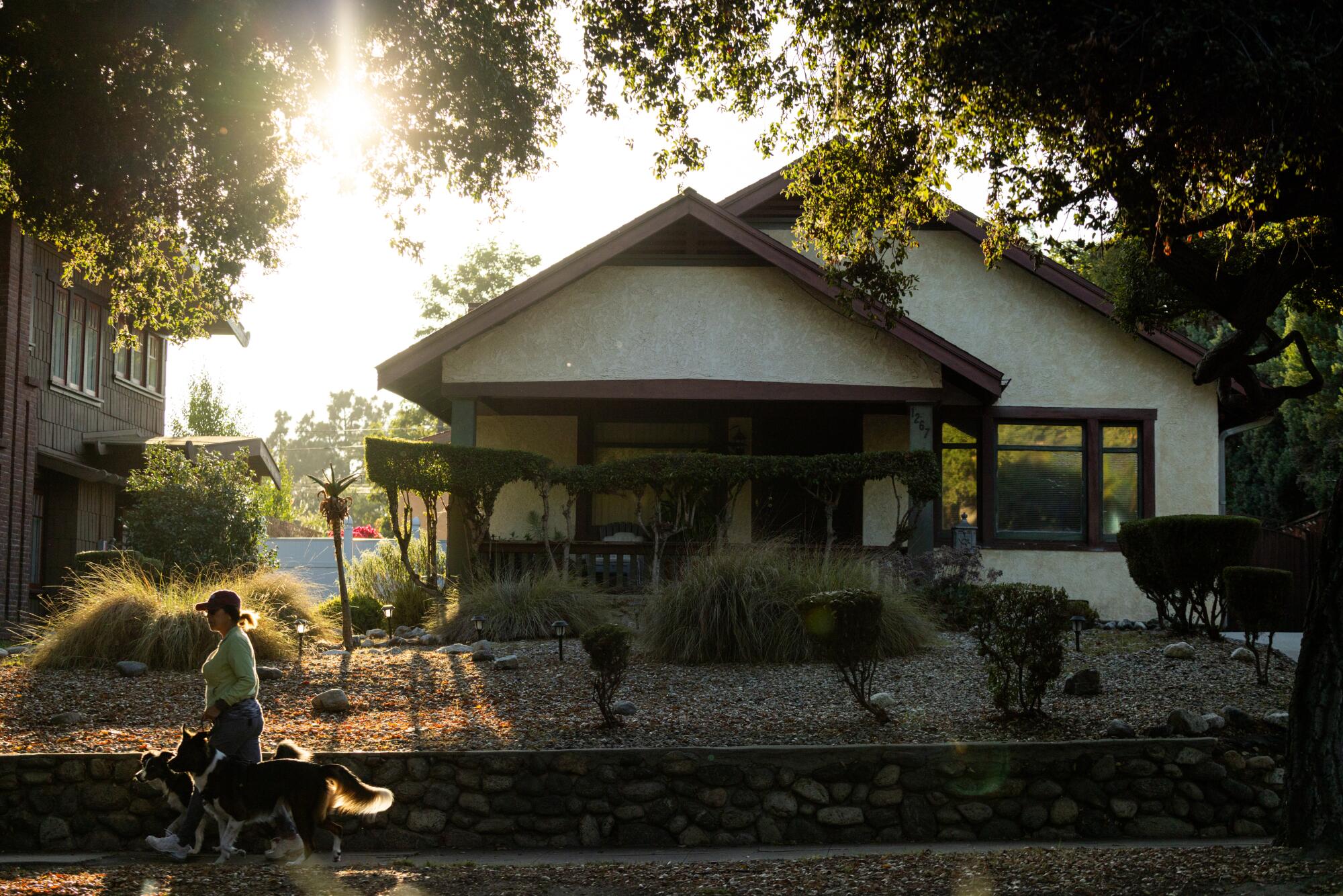 Un bungalow femenino pasea al perro junto a una casa de estilo artesanal en el cielo.