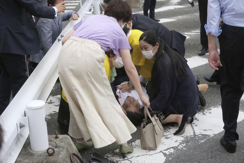 El ex primer ministro japonés Shinzo Abe, al centro, yace en el piso tras ser baleado el viernes 8 de julio de 2022, en Nara, en el oeste de Japón. Abe presentaba falla cardiaca, indicó la televisora NHK. (Kyodo News vía AP)