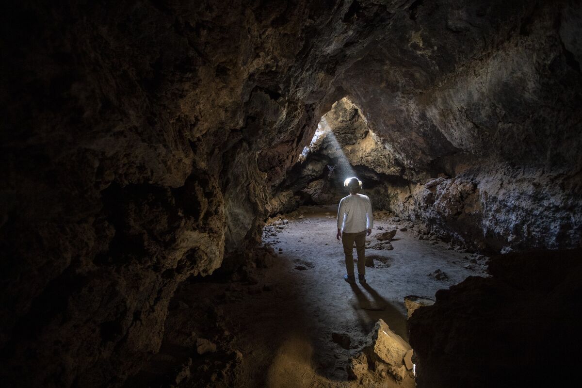 A shaft of light illuminates a lava tube, formed long ago by molten lava in the Mojave National Preserve.