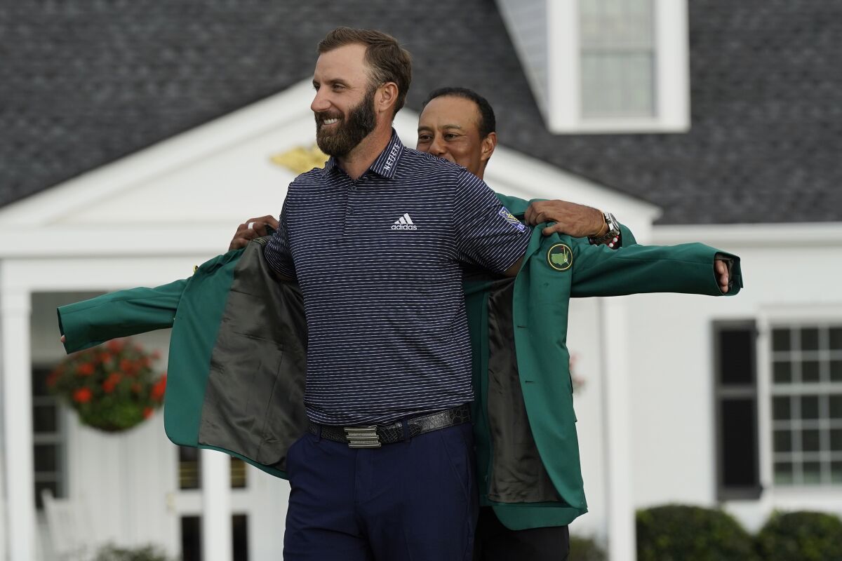 Tiger Woods helps Dustin Johnson into the green jacket. 