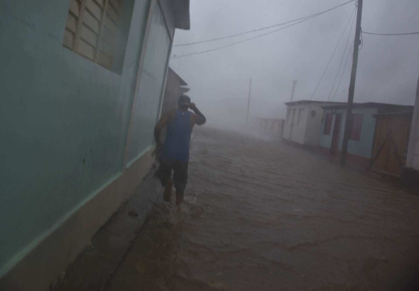 A resident runs in as flooded street as Hurricane Matthew roars over Baracoa, Cuba, Tuesday, Oct. 4, 2016.
