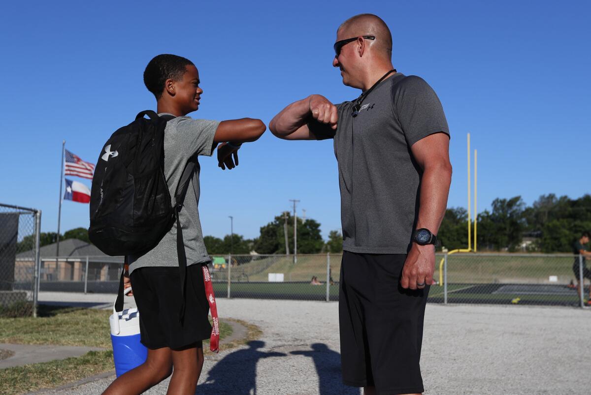 Head football coach Bob Wager, right, and sophomore Cameron Conley greet Thursday at Arlington Martin High School.