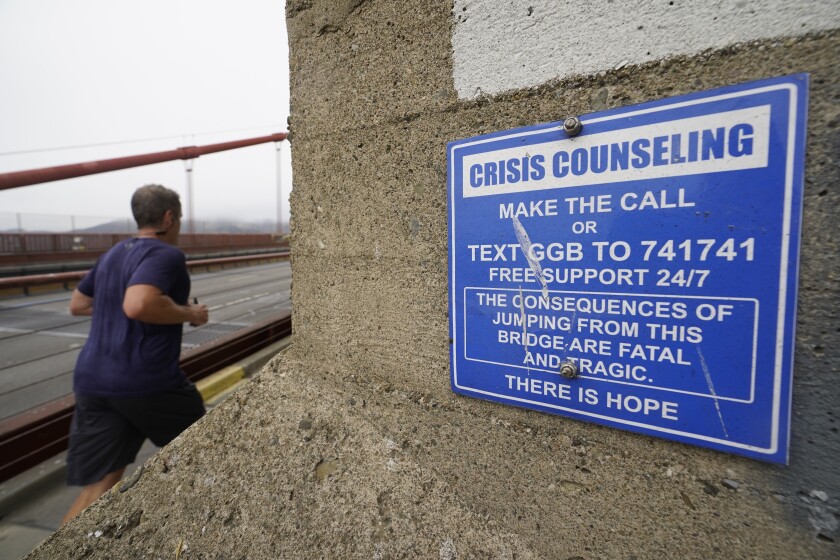 A man jogs on a bridge past a sign offering crisis counseling