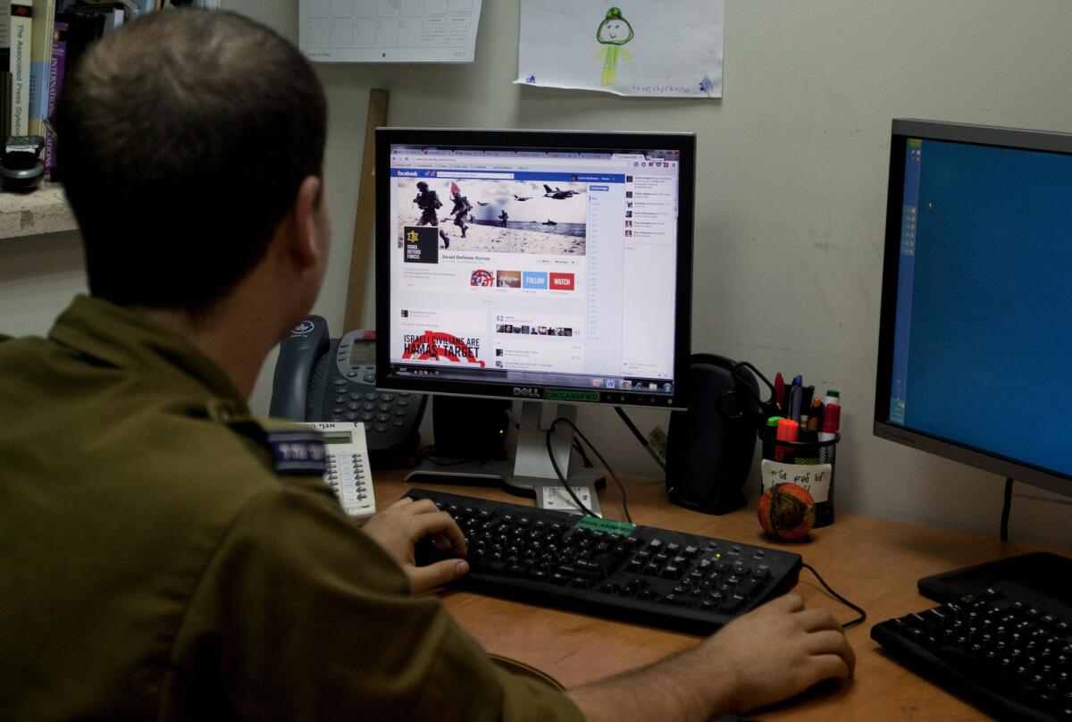 An Israeli soldier looks at the Israel Defense Forces Facebook page in Jerusalem. As many as 550 bilingual students could join a project to post, tweet and blog pro-Israel content in return for scholarships and stipends.