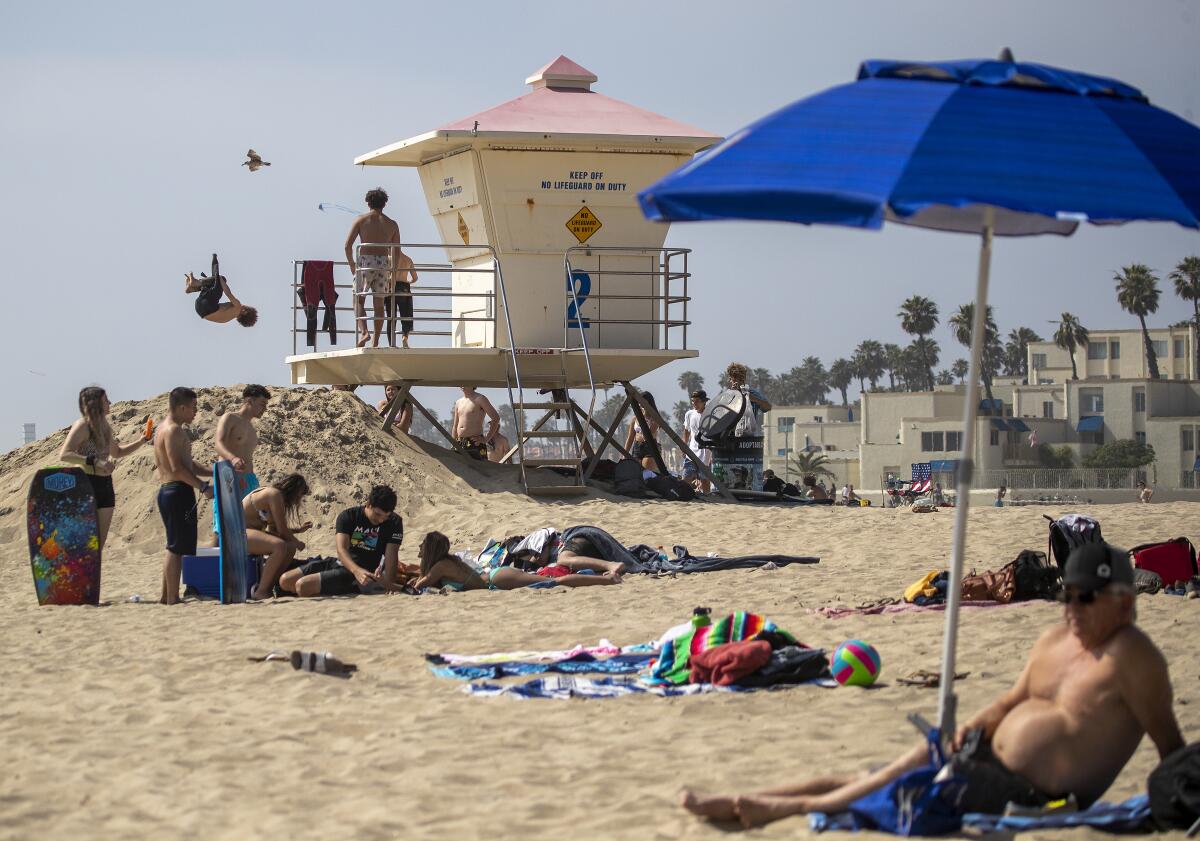 Children do flips off the lifeguard tower while others relax on the last day of open beaches in Huntington Beach after Gov. Gavin Newsom on Thursday announced the "hard close" of all Orange County beaches.
