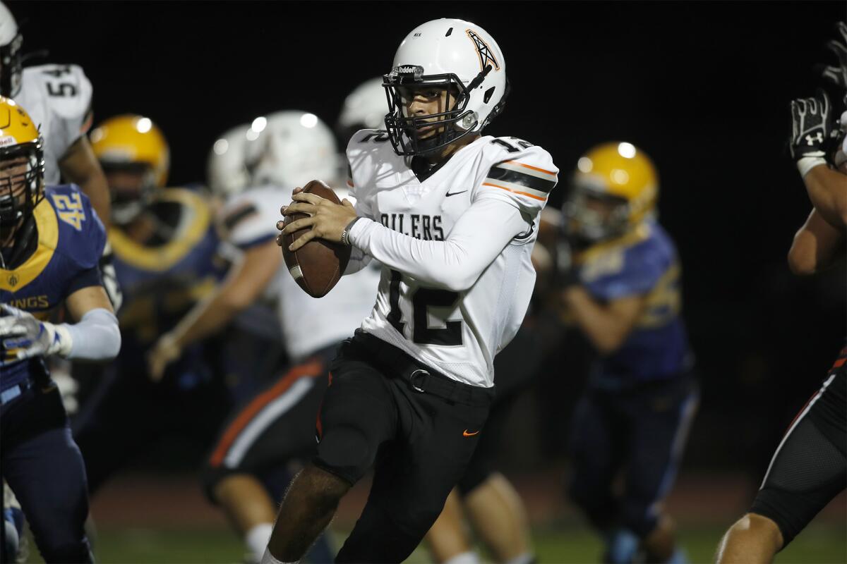 Huntington Beach quarterback Brandon Cannella is forced to scramble against Marina in a nonleague game at Westminster High on Friday.