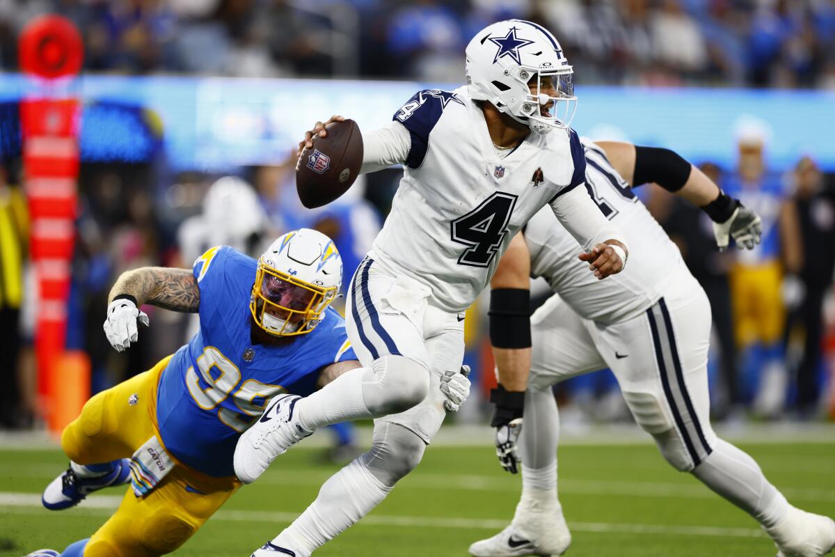 Chargers defensive lineman Scott Matlock, left, tries to tackle Dallas Cowboys quarterback Dak Prescott.