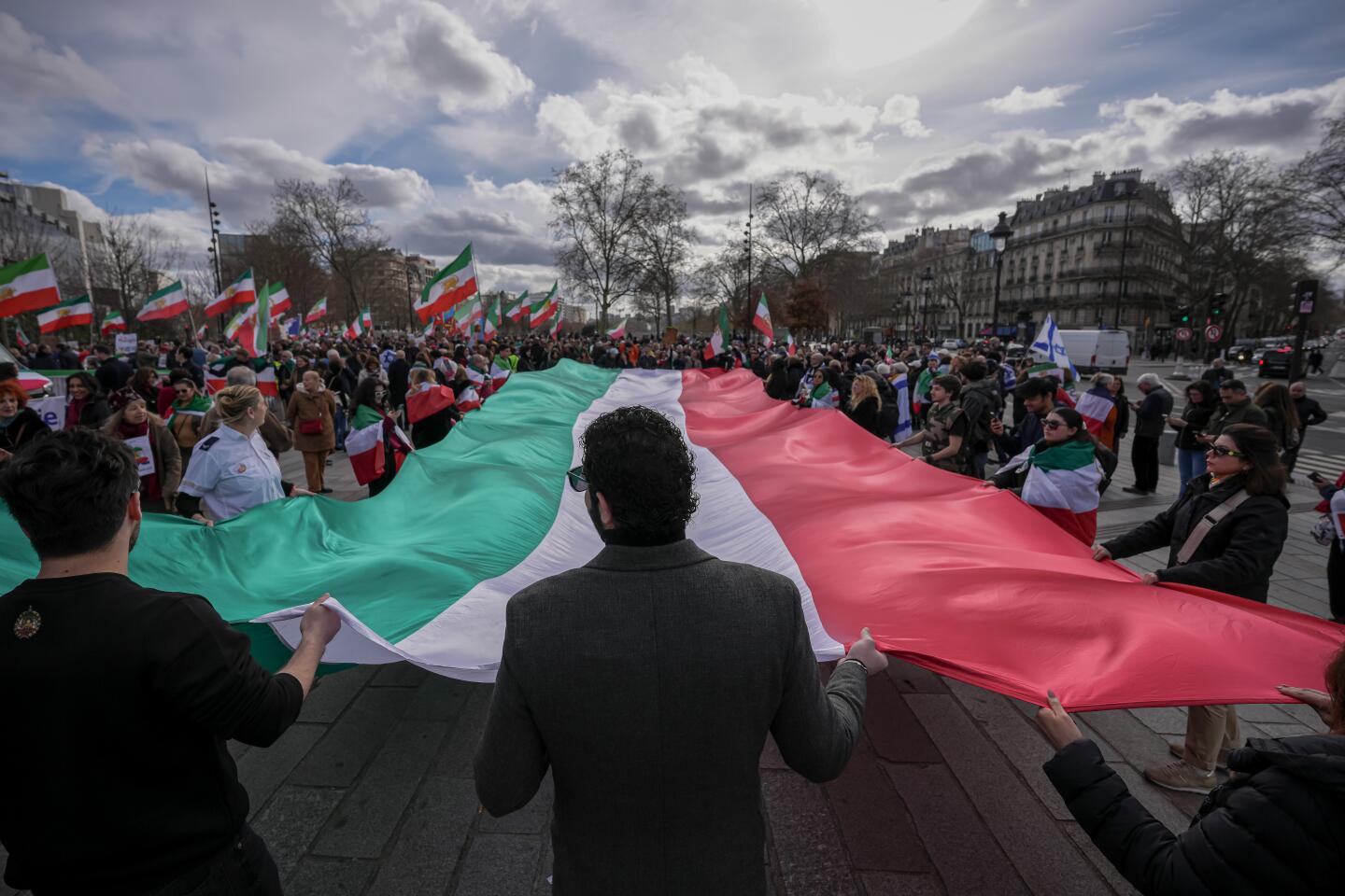 Members of the large Iranian diaspora in France hold an Iranian flag during a demonstration in reaction to the U.S. and Israeli strikes on Iran on Sunday, March 1, 2026, in Paris, France. (AP Photo/Aurelien Morissard)
