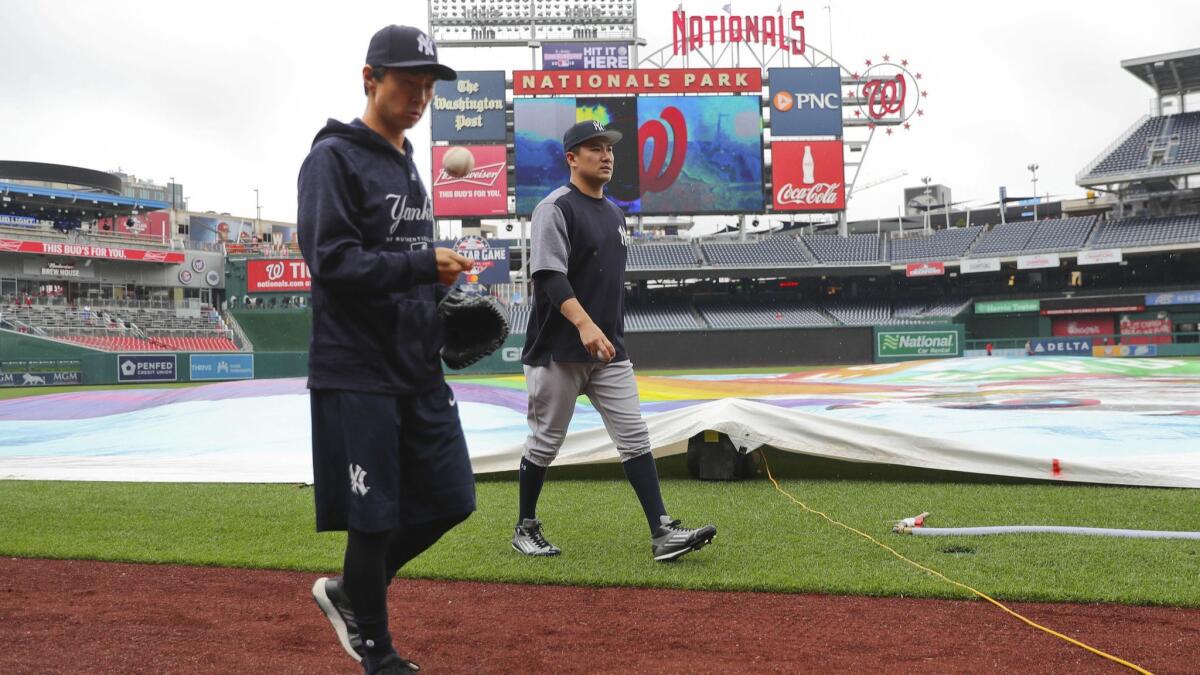 New York Yankees pitcher Masahiro Tanaka, right, and his translator, Shingo Horie, walk off the field at Nationals Park after it was announced that both of Wednesday's games were postponed.