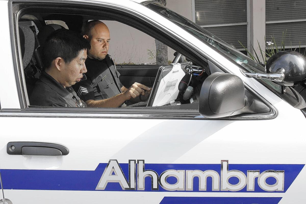 Volunteer Walter Yu, in passenger's seat, engages members of Alhambra's Chinese-speaking population on Weibo as he rides with Sgt. Edward Rodriguez on patrol.