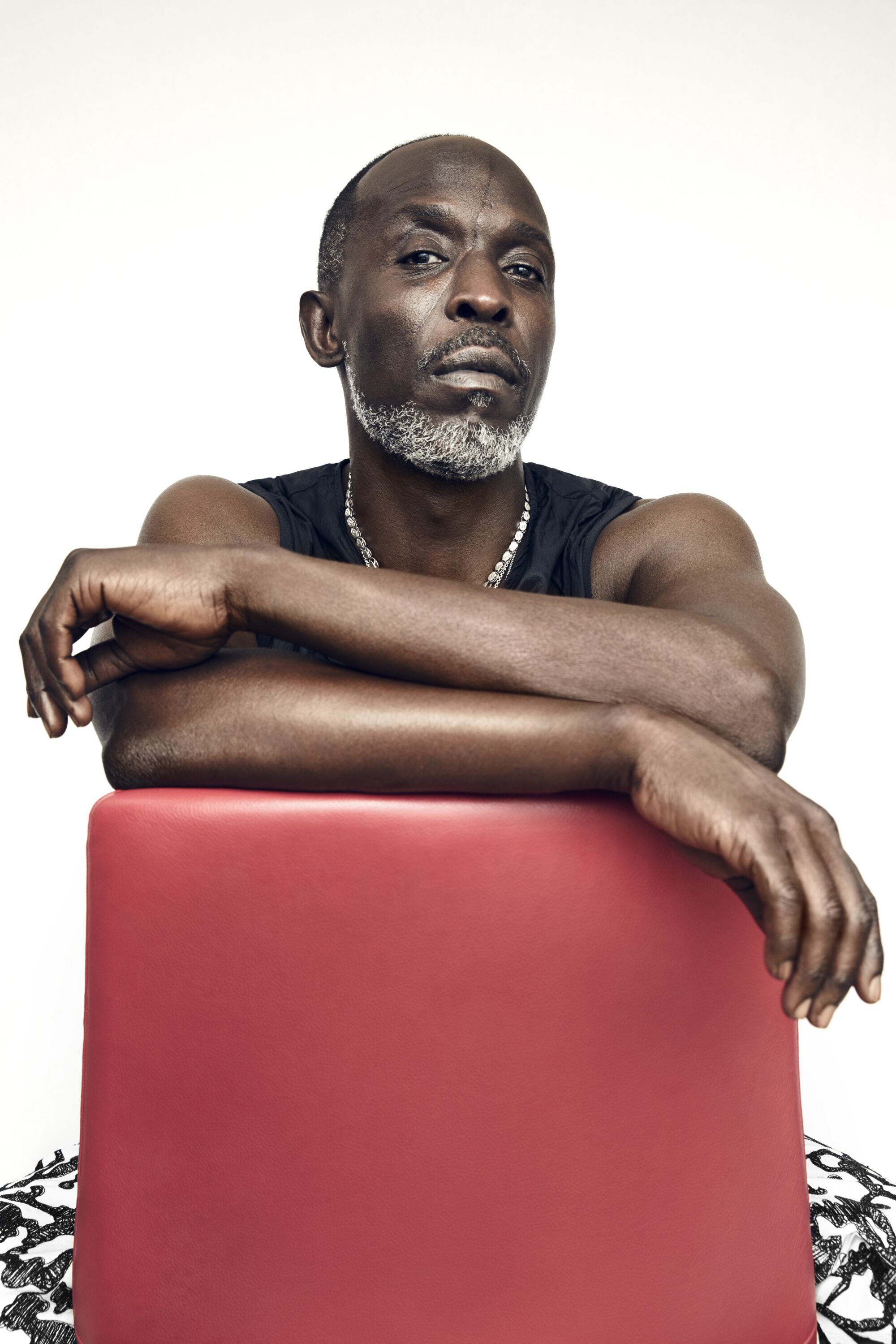 Michael K. Williams, perched over the back of a red chair. 