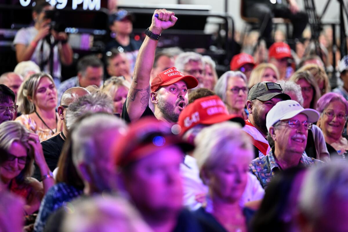 A fan raises his fist while listening to a speaker