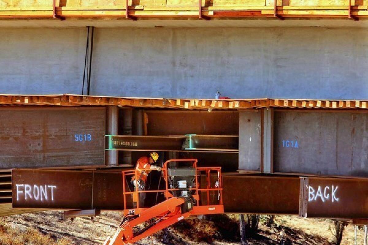 A laborer works under the Mulholland Bridge, which crosses the 405 Freeway in Los Angeles. The bridge project necessitates the complete closure of the freeway for a weekend, potentially causing a massive traffic nightmare across the region.